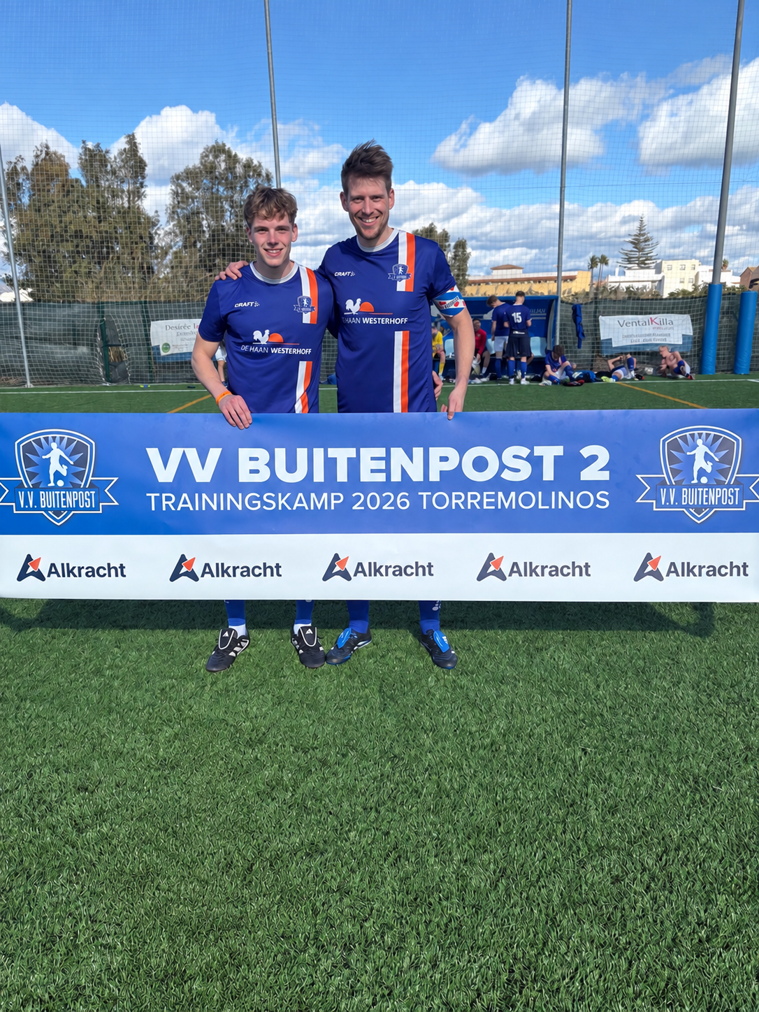 Jesper Daan Ploegsma met een teamgenoot van vv Buitenpost 2 bij het AIKracht-spandoek op trainingskamp in Torremolinos, 2026